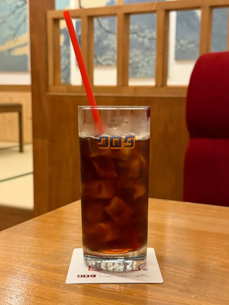 빨간 벨벳 소파 앞 원목 테이블에 놓인 쿠로다 아이스 커피